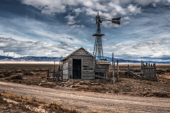 Abandoned cabin and windmill in a dry landscape