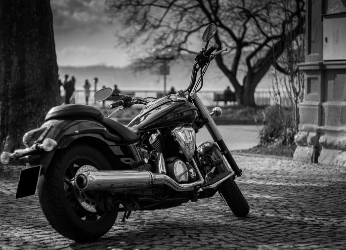 Monochrome motorcycle parked on cobblestone street