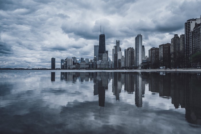 Chicago skyline reflected in water under cloudy sky