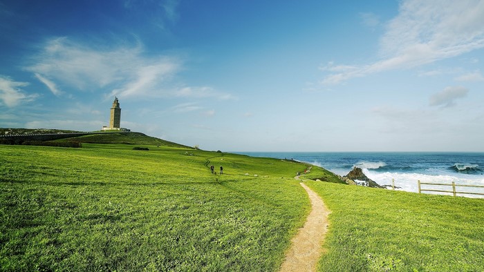 Tower of Hercules lighthouse on a grassy hill overlooking the ocean
