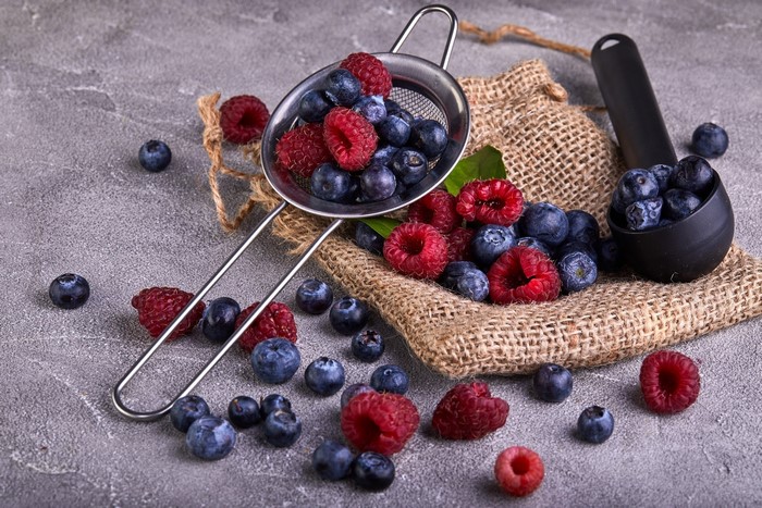 Raspberries and blueberries in a sieve and scoop