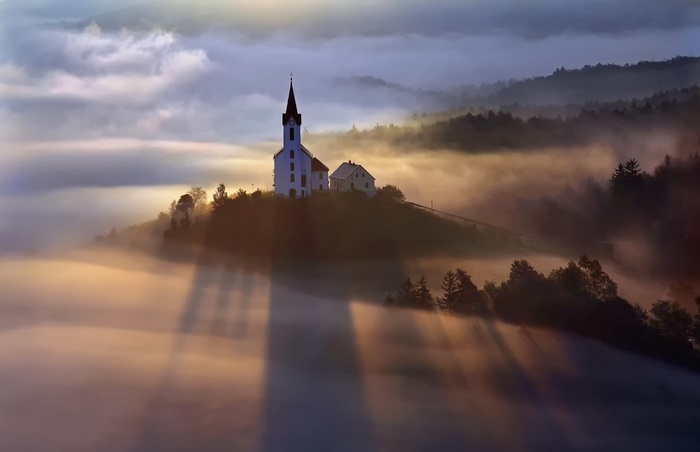 Church on a hill in fog with sunbeams