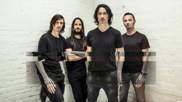 Gojira band members posing against a brick wall