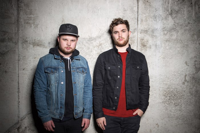 Royal Blood duo standing against a concrete wall