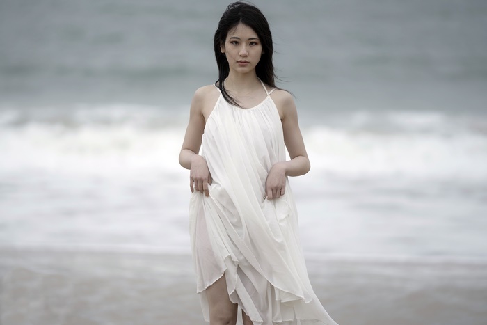 Young Asian woman in white dress on beach