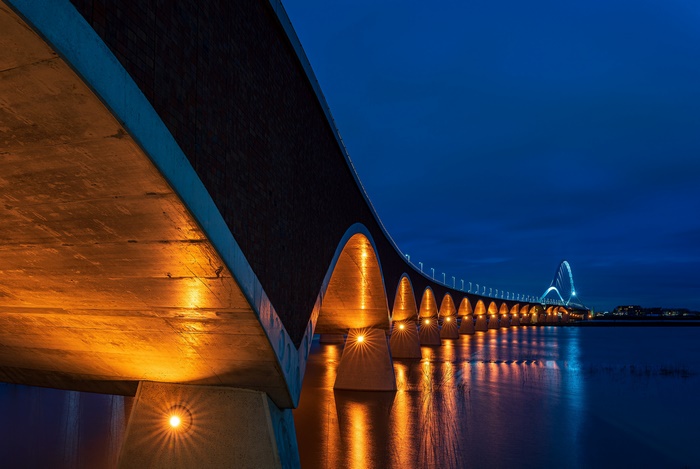 Bridge illuminated at night over water