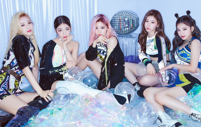 ITZY members posing in colorful outfits with disco balls