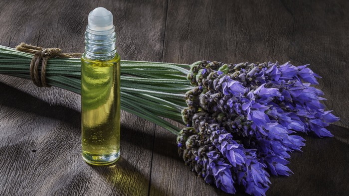 Lavender essential oil roller bottle with lavender flowers