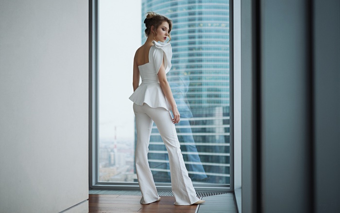 Brunette woman in white suit by the window