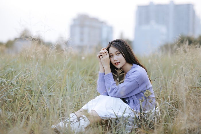 Asian woman in a purple sweater sitting in grass