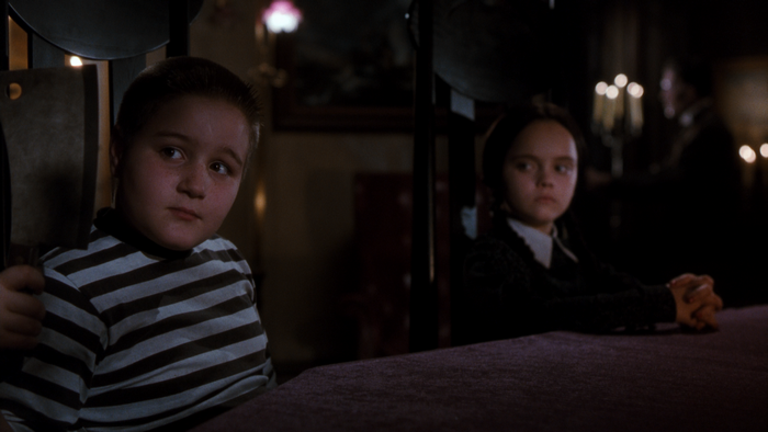 Pugsley and Wednesday Addams at a table