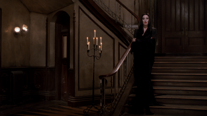 Morticia Addams standing on a staircase