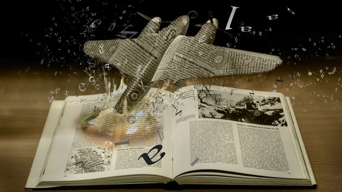Book with airplane made of newspaper and flying letters