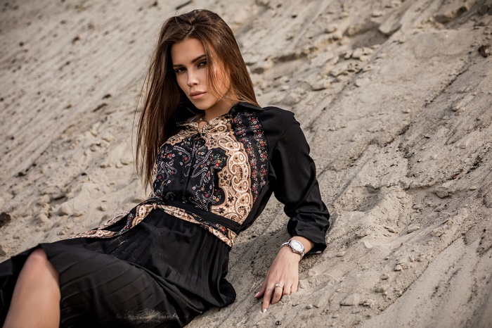 Brunette woman in a black dress on sand