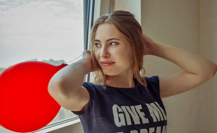 Woman with red balloon by the window