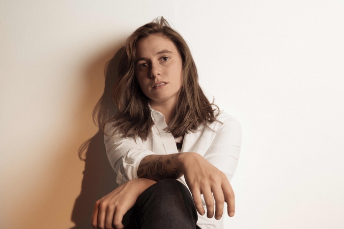 Julien Baker sits against a wall