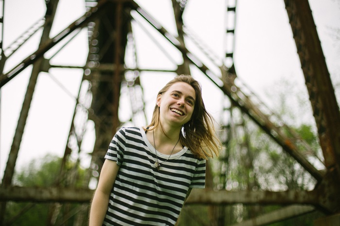 Julien Baker smiles under a bridge