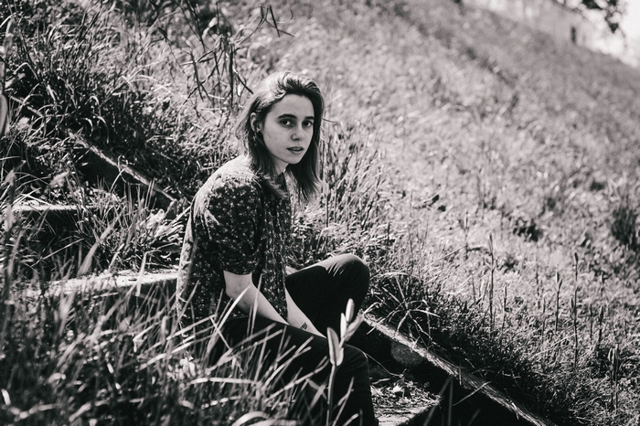 Julien Baker sitting on steps in grass