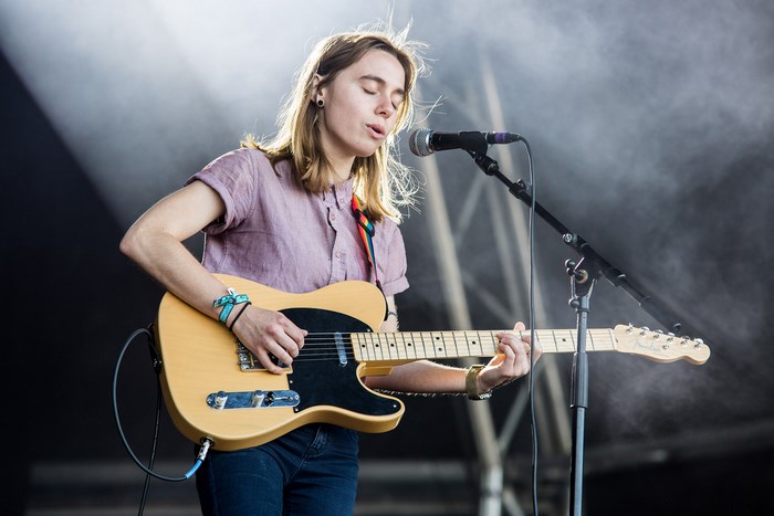 Julien Baker performs on stage with a guitar