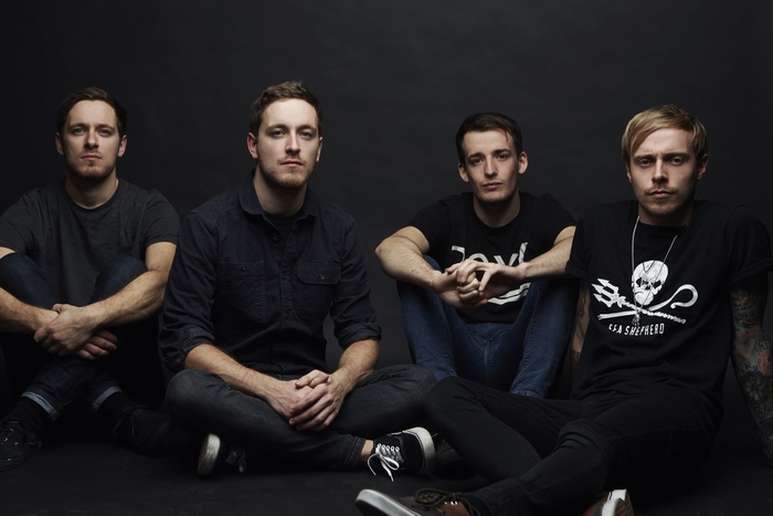 Architects band members sitting against a dark background