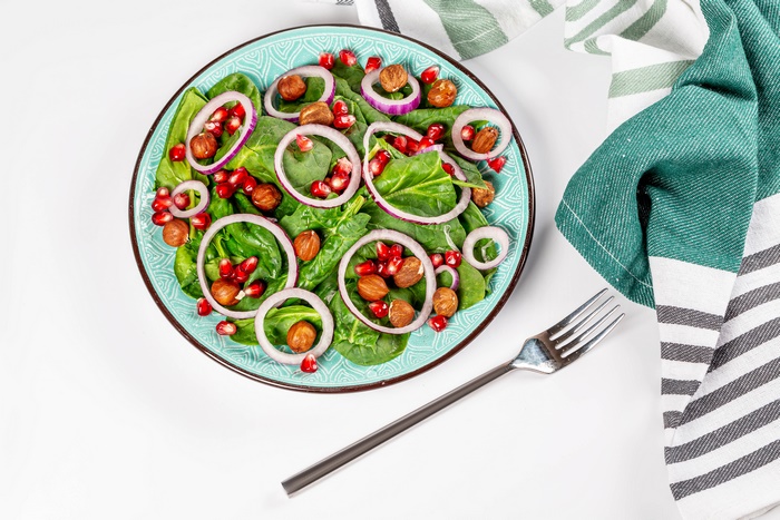 Spinach salad with pomegranate, hazelnuts, and red onion