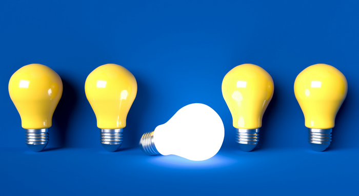 One glowing light bulb among four yellow ones