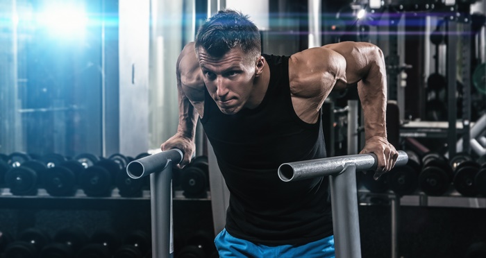 Bodybuilder performing dips in a gym