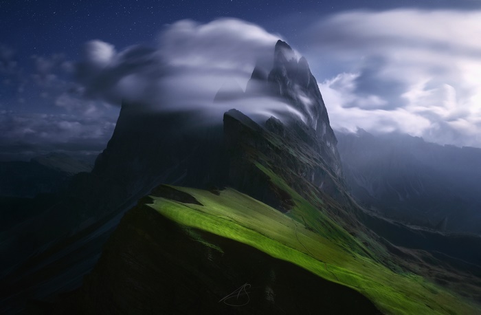 Mountain peaks shrouded in clouds under a starry night sky