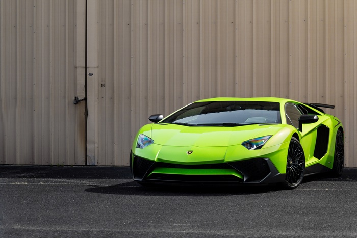 Green Lamborghini Aventador SV parked in front of a building