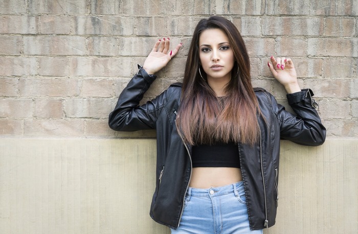 Woman in Leather Jacket Posing Against Wall