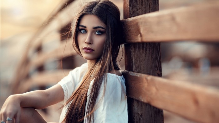 Model leaning against a wooden fence