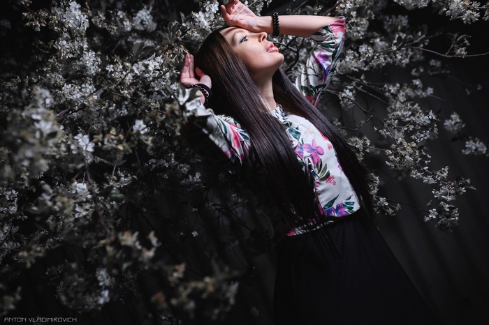 Woman with long black hair posing near flowers