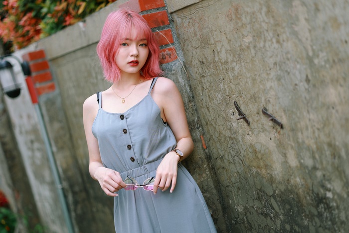 Woman with pink hair wearing a grey jumpsuit