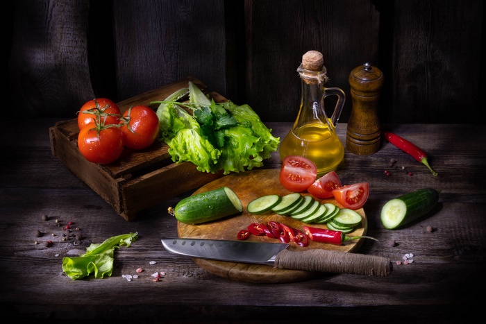 Still life with tomatoes, cucumbers, lettuce, oil, and spices