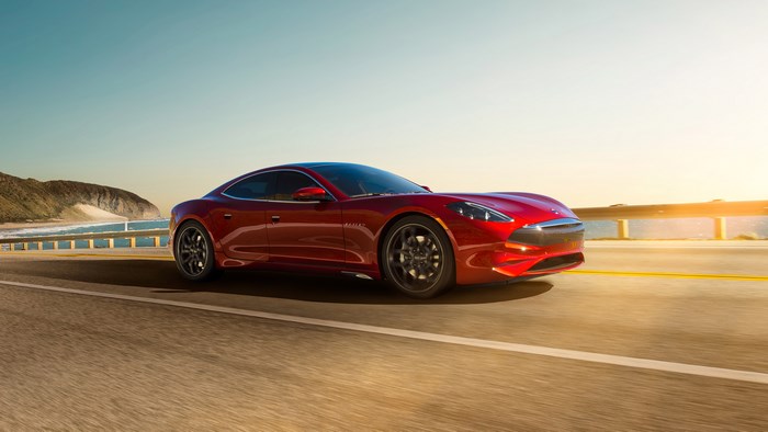 Red Karma Revero GT driving on a coastal road