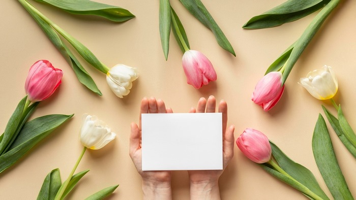 Hands holding a blank card surrounded by tulips