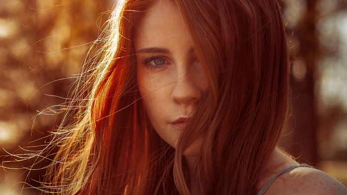 Redhead woman with windblown hair in sunlight