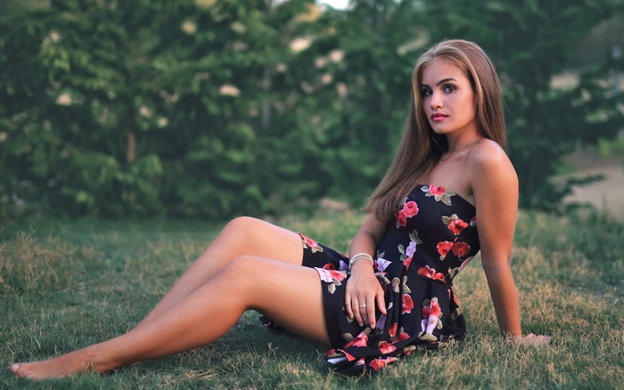 Woman in a floral dress sitting on grass