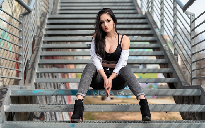 Woman with black hair and brown eyes sitting on stairs