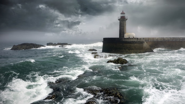 Lighthouse on a rocky coast during a storm