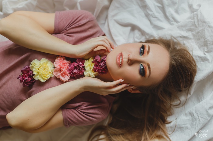 Woman lying down with flowers around her neck