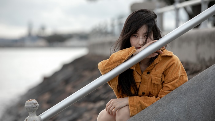 Asian woman with black hair leaning on railing