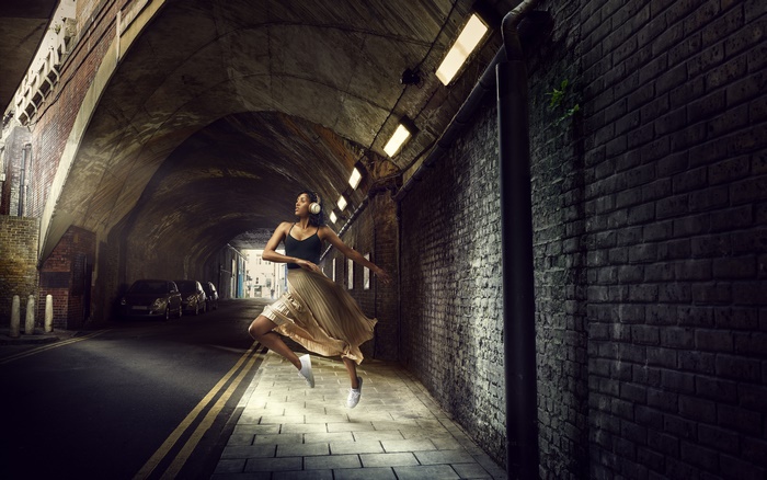Woman with headphones dancing in a tunnel