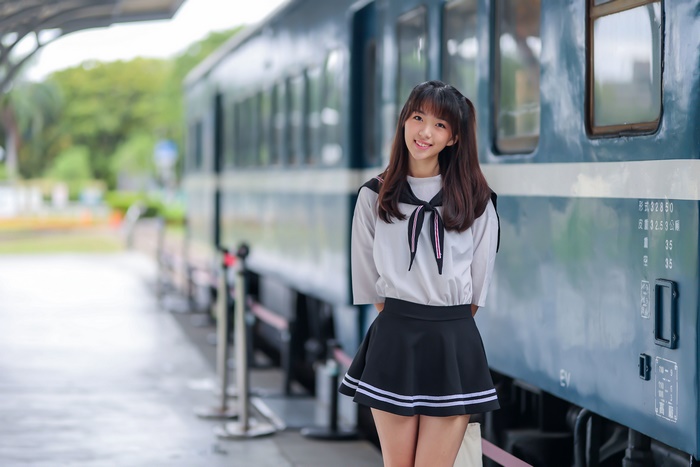 Asian woman in school uniform at train station