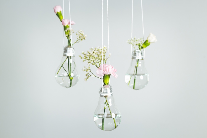 Three hanging lightbulb vases with flowers