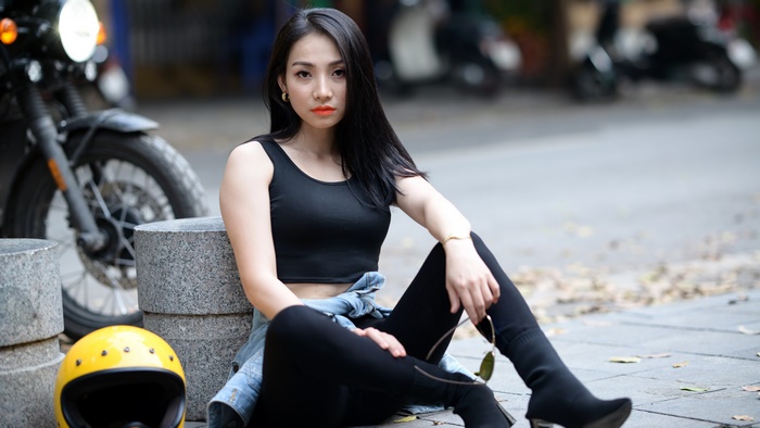Asian woman with black hair sitting by a motorcycle