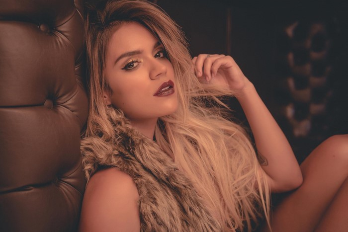 Karol G posing in a fur vest