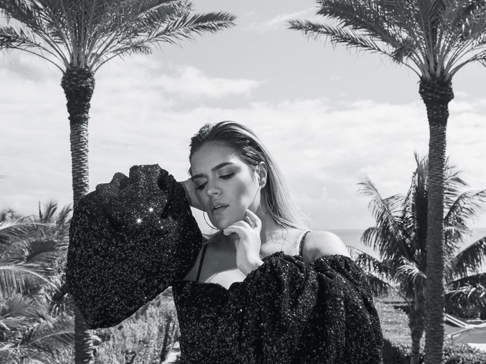 Karol G posing outdoors with palm trees