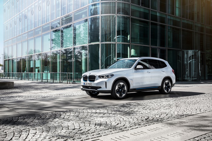 White BMW iX3 electric SUV parked in front of a modern building