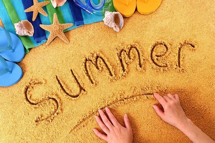 Summer written in sand with beach items